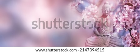 beautiful cherry blossoms around the buddha statue in springtime, sunshine on idyllic garden with cherry tree and budda on blurred sky background with copy space, floral asian culture concept