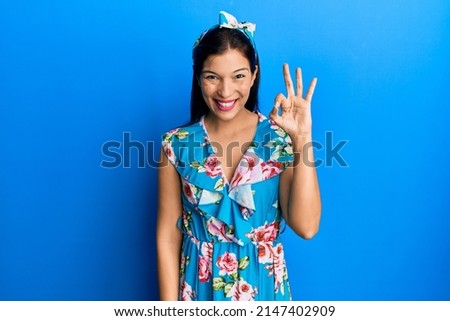 Young latin woman wearing casual clothes smiling positive doing ok sign with hand and fingers. successful expression. 