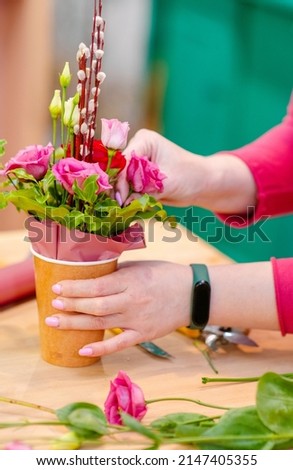 Hands of a florist creating a flower arrangement for Easter close-up  Royalty-Free Stock Photo #2147405355