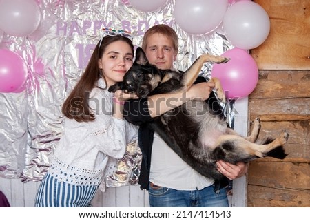 A guy and a girl hold a dog in their arms and take pictures during a party