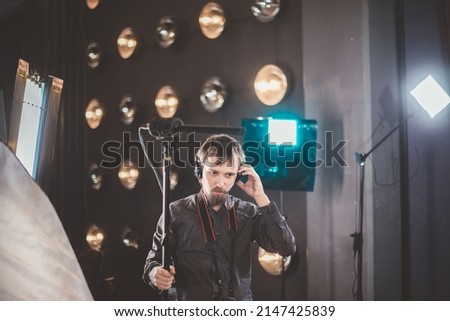 Sound engineer with a microphone on the set. A professional sound engineer at work on the filming of a movie, commercial or TV series. Filming process indoors, studio Royalty-Free Stock Photo #2147425839