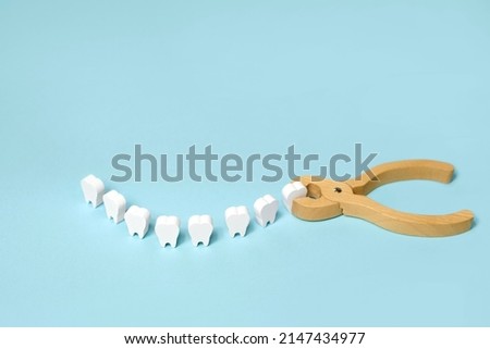 Tooth extraction with a dental instrument with forceps.  A model of teeth in the shape of a smile. Problems with wisdom teeth, toothache Royalty-Free Stock Photo #2147434977