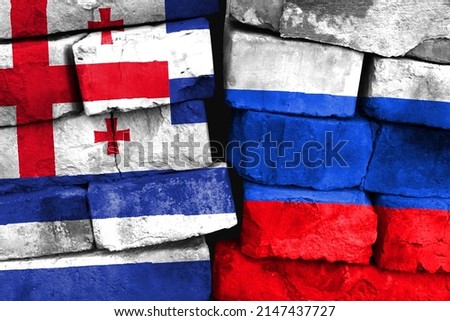 Concept of the relationship between Adjara and Russia with two painted flags on a damaged brick wall