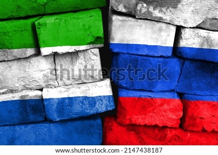 Concept of the relationship between Sierra Leone and Russia with two painted flags on a damaged brick wall