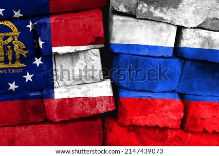 Concept of the relationship between State of Georgia and Russia with two painted flags on a damaged brick wall