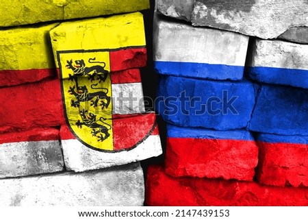 Concept of the relationship between Carinthia and Russia with two painted flags on a damaged brick wall