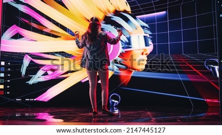 Digital Artist Using VR Software to Create a 3D Piece of Art: Designing a Stylish Futuristic Portrait in Interactive Environment on a Big Digital Screen. Female Designer Using Headset and Controllers. Royalty-Free Stock Photo #2147445127