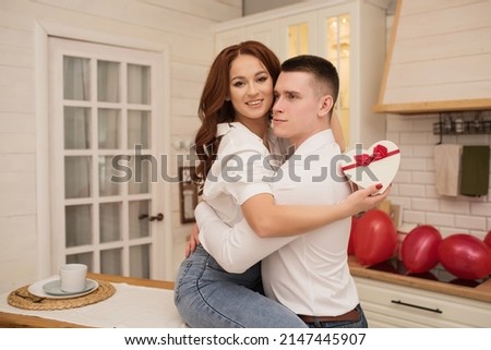 a gift for Valentine's day, birthday. the girl hugs her husband and holds a gift box in the form of a heart, the concept of congratulations and celebration