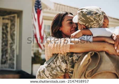 American serviceman saying his goodbyes to his family at home. Brave soldier embracing his wife and daughter before leaving for war. Patriotic man leaving to go serve his country in the military.
