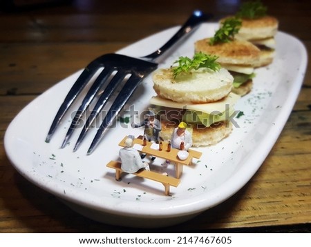 Miniature figure and food on the white plate. Food photography concept design. Conceptual photography. Unfocus and blurred view.