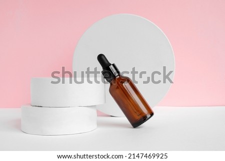 Amber glass dropper cosmetic bottle, white podium. Natural skin care SPA beauty product design. Mineral organic oil on pink background. Mock-Up. Oily pipette. Face and body treatment. Front view.