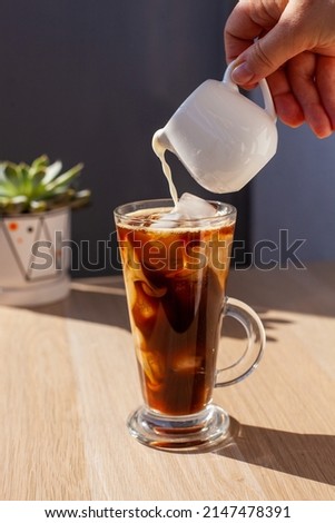 
Transparent glass of black coffee with iced milk