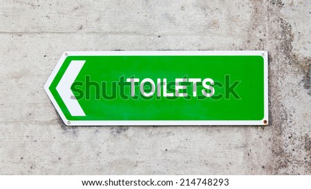 Green sign on a concrete wall - Toilets