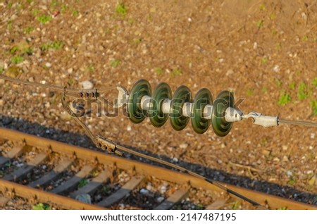 Insulator on high-voltage power line. Blurred railway track background.