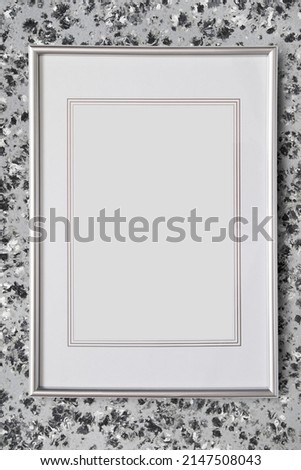 Empty silver fillet picture frame hanging on grey wall