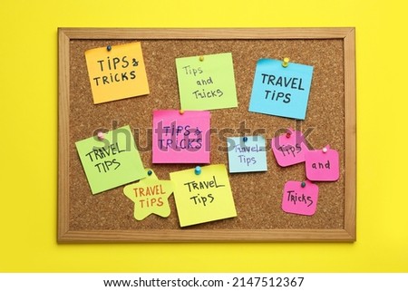Colorful paper notes pinned to cork board on yellow wall. Travel tips and tricks