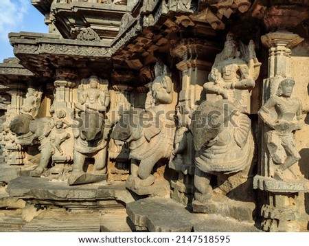 Stock photo of ruined ancient sculpture of Hindu trinity god sitting on elephant, idol carved out off gary color granite sunlight falling on idol, Picture captured at Khidrapur, Maharashtra, India.