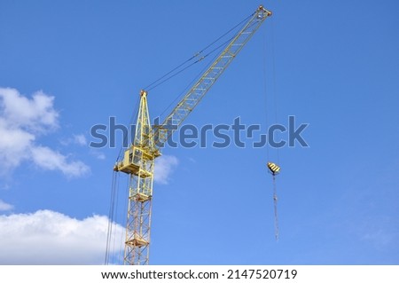 A yellow tower crane is installed at a construction site for the construction of a new building.