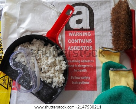Close up asbestos and fibers, mask, filter goggles. Asbestos bag in the background. Barrier tape, warning forbidden acces hazard. Asbestos removal. Protection Asbestosis, lungcancer or mesothelioma. Royalty-Free Stock Photo #2147530211