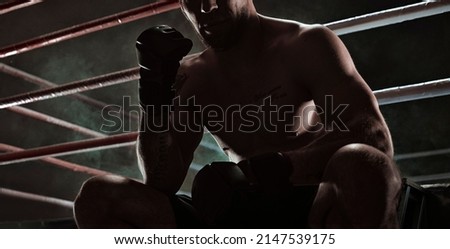 Kickboxer is sitting near the ring and motivatingly shows his fist in the overlay. Sports competitions. Fight night. The concept of mixed martial arts. MMA