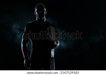 Kickboxer with a belt on his shoulder poses against a background of smoke. Sports competitions. Fight night. The concept of mixed martial arts. 