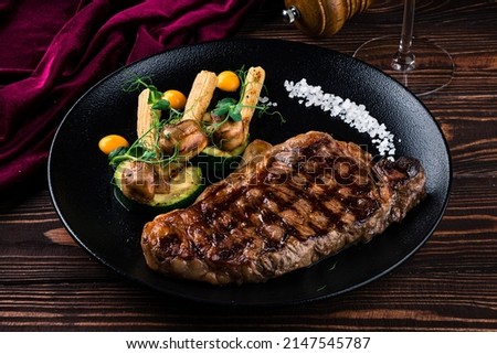 steak and grilled vegetables, Grilled striploin steak with spices and herbs, strip steak New York strip. Beef T-Bone steak on dark background Royalty-Free Stock Photo #2147545787