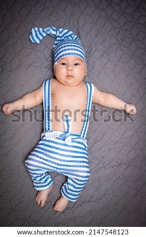 Little sweet young kid lying. Funny cute baby in blue costume.