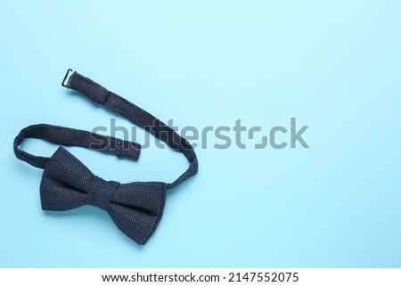 Stylish bow tie on light blue background, top view. Space for text