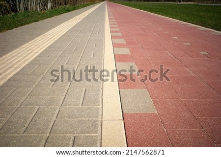 Pedestrian and bike paths converge on the horizon. Perspective. A special relief strip on the pavement for blind people.