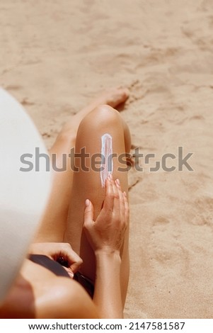 Sun protection. Closeup on female hand applying solar sun cream on Leg. Skincare. Woman smear sunscreen moisturizing lotion on her smooth tanned legs
