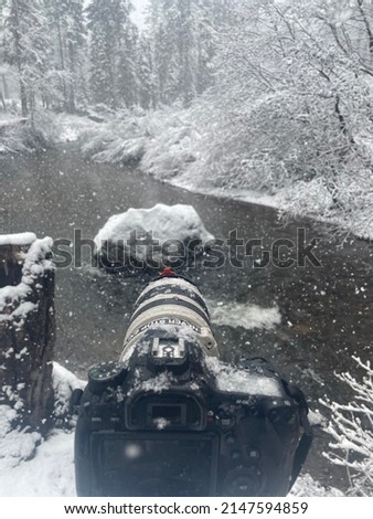 Camera in the snow taking pictures of a river