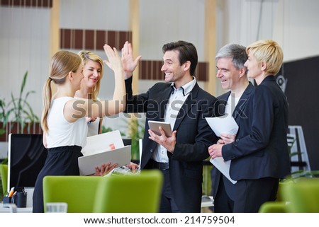 Successful team of business people giving high five in the office Royalty-Free Stock Photo #214759504