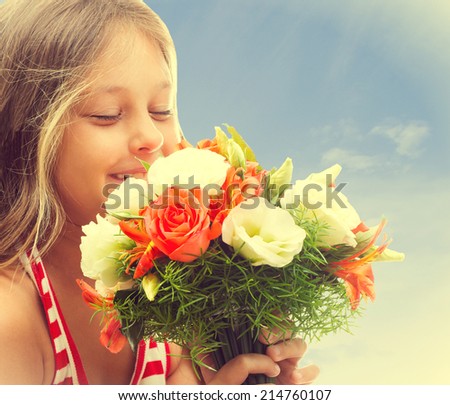 beautiful little girl smelling a bouquet of roses 