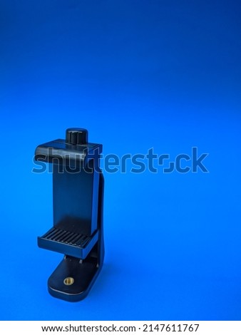 A black plastic phone holder for tripod with blue background 