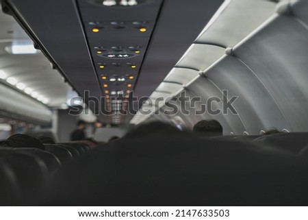 no smoking sign light up on ceiling of airplane cabin above passenger seat that mean cigarette is prohibited in flight
photo with noise and partly blured
