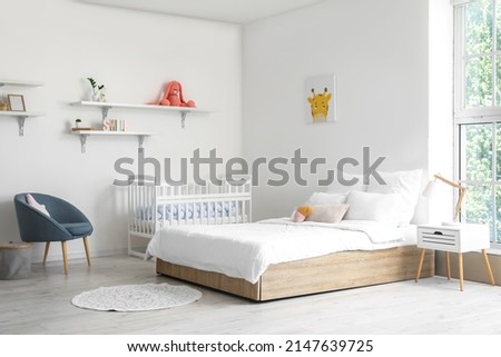Modern interior of cozy room with big bed and comfortable baby crib Royalty-Free Stock Photo #2147639725