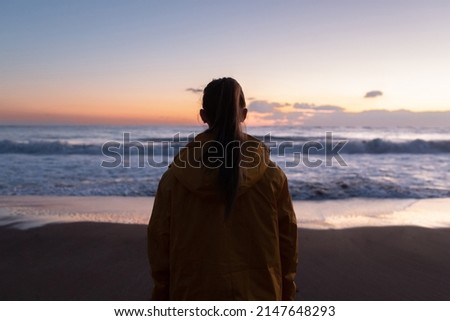 Girl in a jacket on the beach at sunset