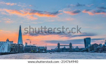 Panoramic view of the new London skyline at sunset with The Shard, Tower Bridge and 20 Fenchurch Street under dramatic sky.