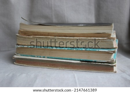 A stack of four old books.  Shabby books on a background of light fabric.