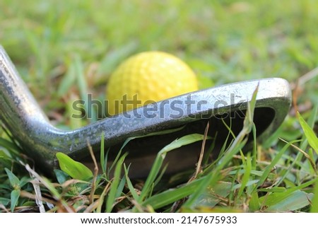 Close up of the head of a golf club and a yellow golf ball