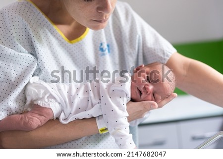 mom who has just given birth in the hospital holds her newborn baby in her arms face down to get rid of gas and prevent colic in the infant. newborn health and care Royalty-Free Stock Photo #2147682047