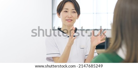 Talking middle aged Asian woman with white robe. Medical consultation. Beauty advisor. Counselor. Royalty-Free Stock Photo #2147685249