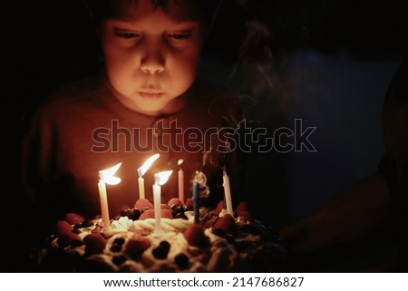Cute caucasian boy blowing up candles pn birthday cake. Image with selective focus