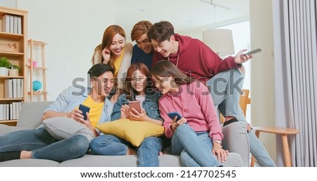 happy asian friends sit sofa watching content on internet talking laughing together on smartphone Royalty-Free Stock Photo #2147702545