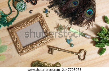 Green  Jewelry and Peacock Feathers With Gold Picture Frame on Wooden Table 