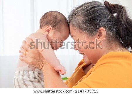 Selective focus grandmother holding in air and touching foreheads with newborn baby, granny expressing understanding candid emotions and love to sweet little child. Happy friendly family concept.