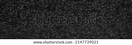 Old black stone wall wide panoramic texture. Rough crushed rock masonry gloomy backdrop. Dark gray abstract background Royalty-Free Stock Photo #2147739021