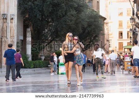 Urban session in the city with two young friends, one blonde and one brunette with long hair, laughing and enjoying together.