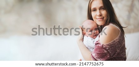 Young mother holding her newborn happy baby