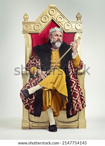 Throne of the kings. Studio shot of a richly garbed king sitting on a throne holding his scepter. Royalty-Free Stock Photo #2147754145